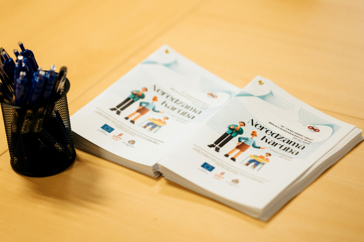 Uz galda novietoti pasākuma "Neredzamā kārtība" izdales materiāli