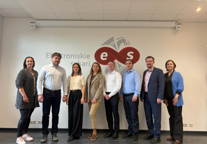 Eight representatives posing in front of the Electronic Communications Office of Latvia logo.
