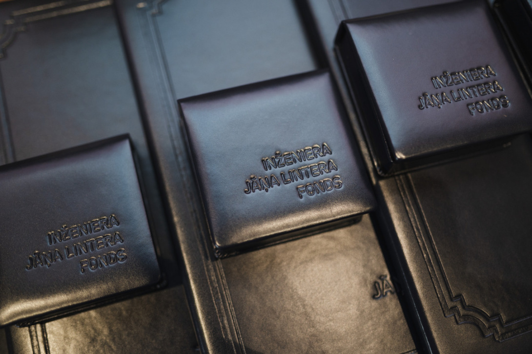Melni ādas futrāļi ar reljefa uzrakstu “Inženiera Jāņa Lintera fonds”